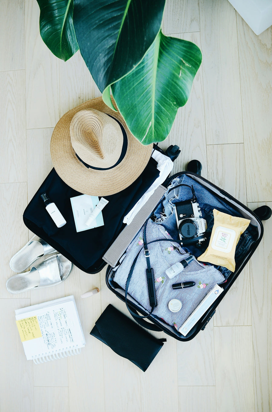 open suitcase with travel essentials and hat